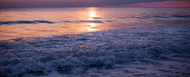 Waves crashing on shore at sunset