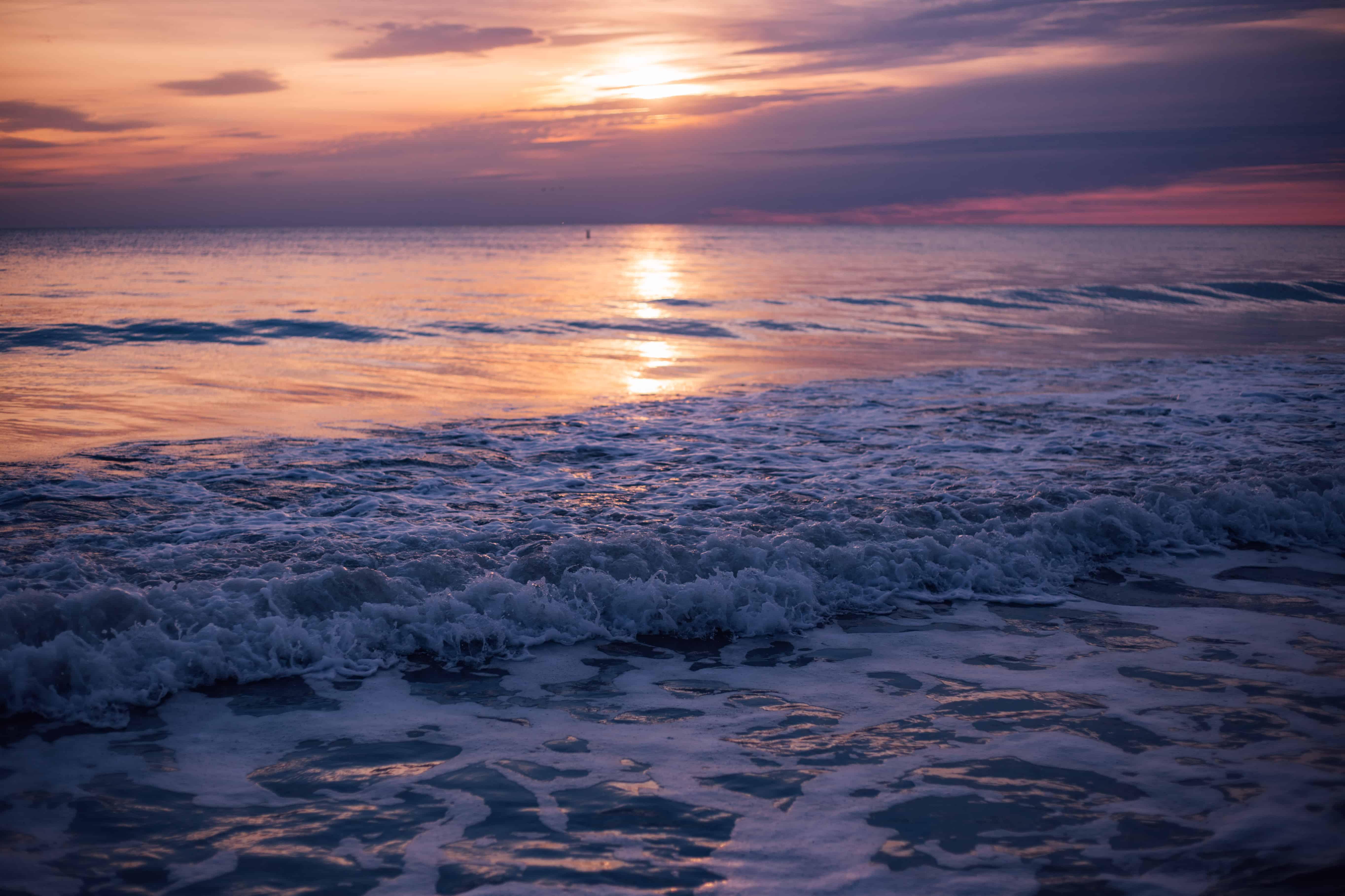 Waves crashing on shore at sunset