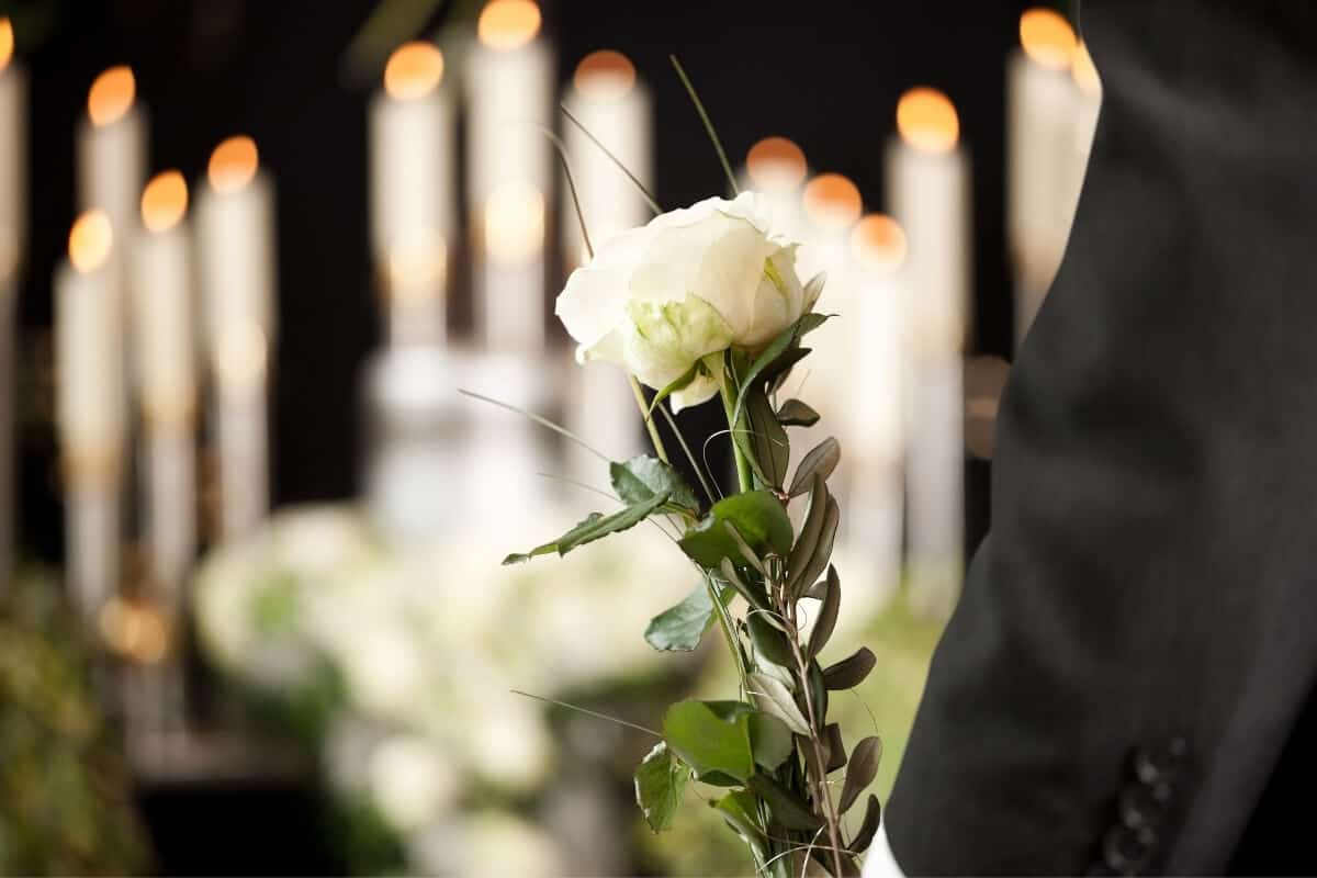 closeup of arms holding white rose with candles in the foreground