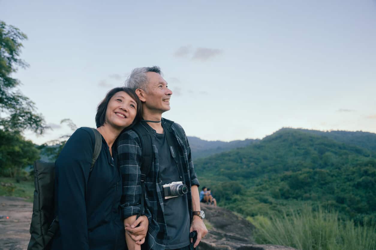 Smiling mature couple enjoying a serene hike, embodying the peace and freedom one might associate with choosing cremation over traditional burial methods.