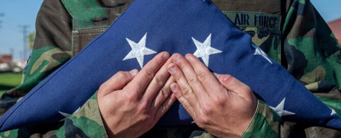 military member holds folded flag at funeral - veteran cremation costs