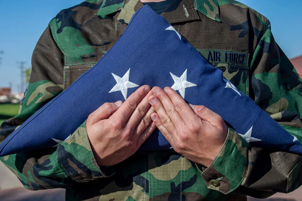 military member holds folded flag at funeral - veteran cremation costs