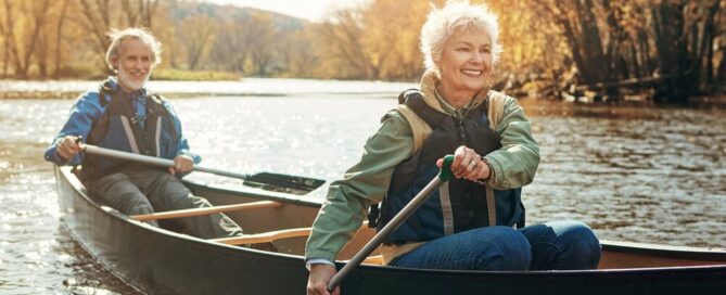 elderly couple kayaking down a river in Autumn.